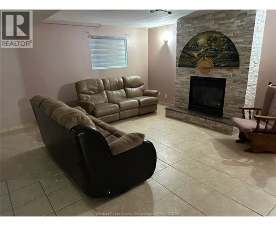 A living room with a stone fireplace and a painting above it.