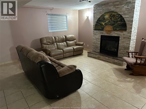 A living room with a stone fireplace and a painting above it.