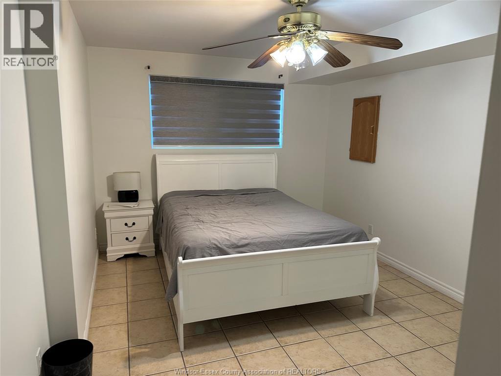 A bedroom with a bed, nightstand, and trash can.