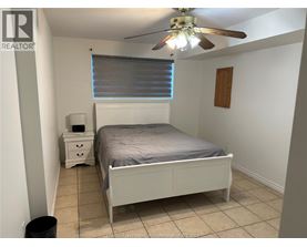 A bedroom with a bed, nightstand, and trash can.