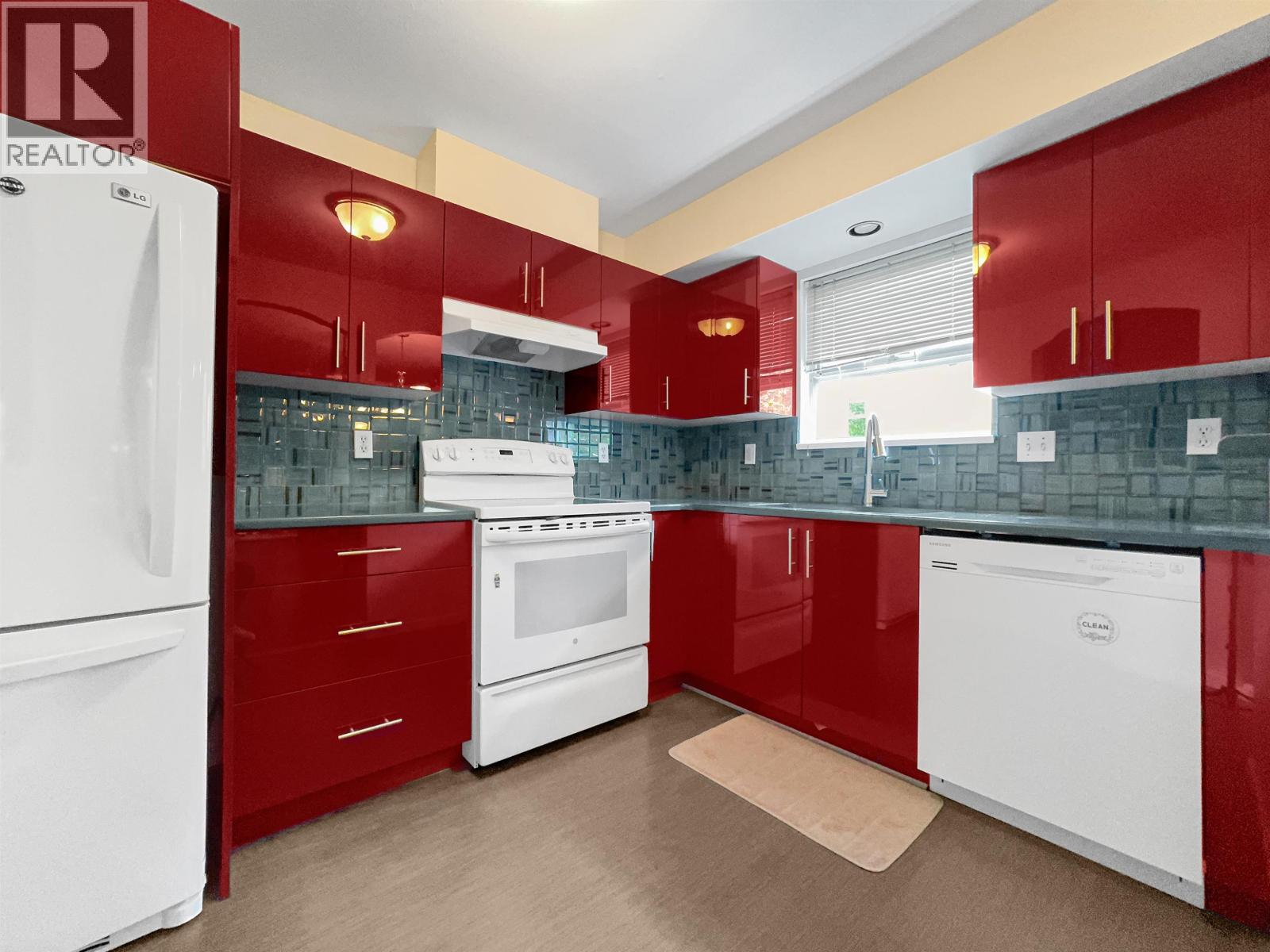 A kitchen with red cabinets and white appliances.