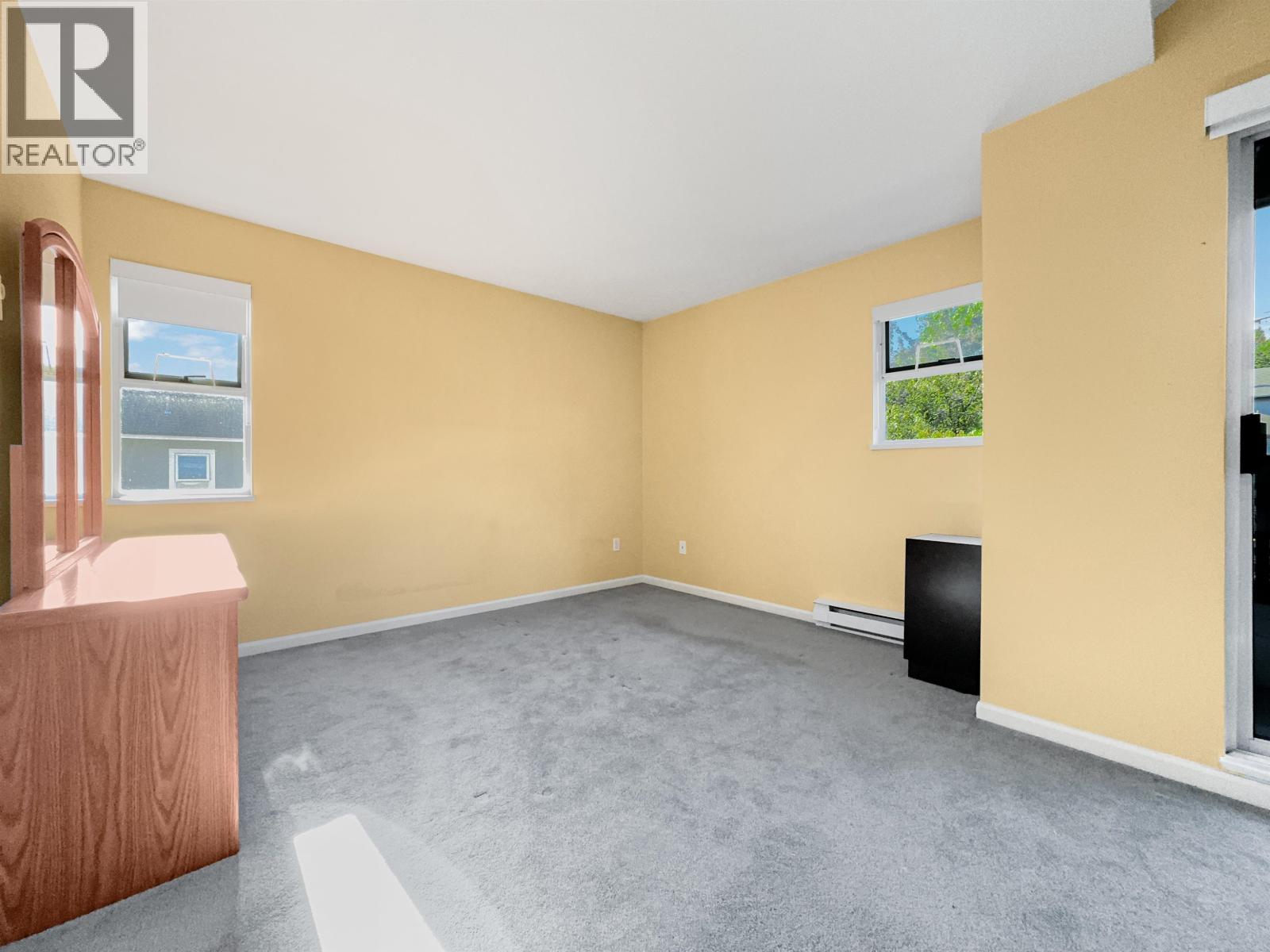 A room with a yellow wall and a window with a view of trees.