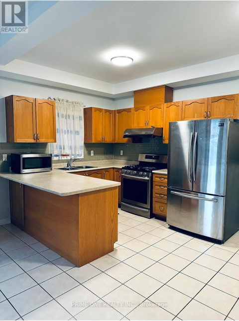 A kitchen with wooden cabinets and a stainless steel refrigerator.