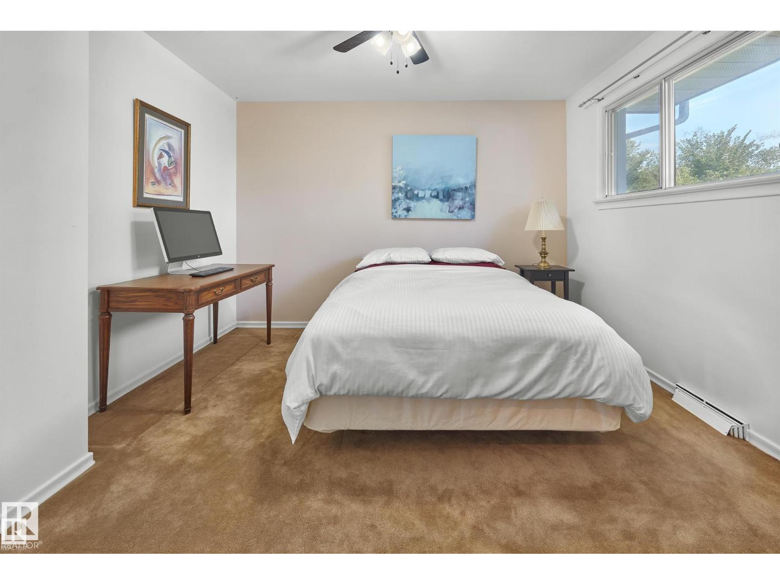 A bedroom with a bed, desk, and window.
