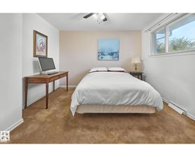 A bedroom with a bed, desk, and window.