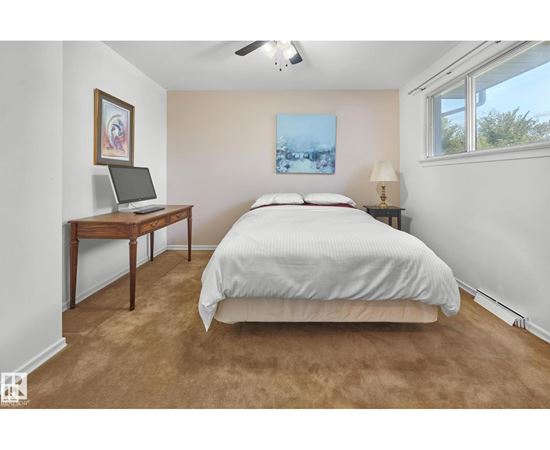 A bedroom with a bed, desk, and window.
