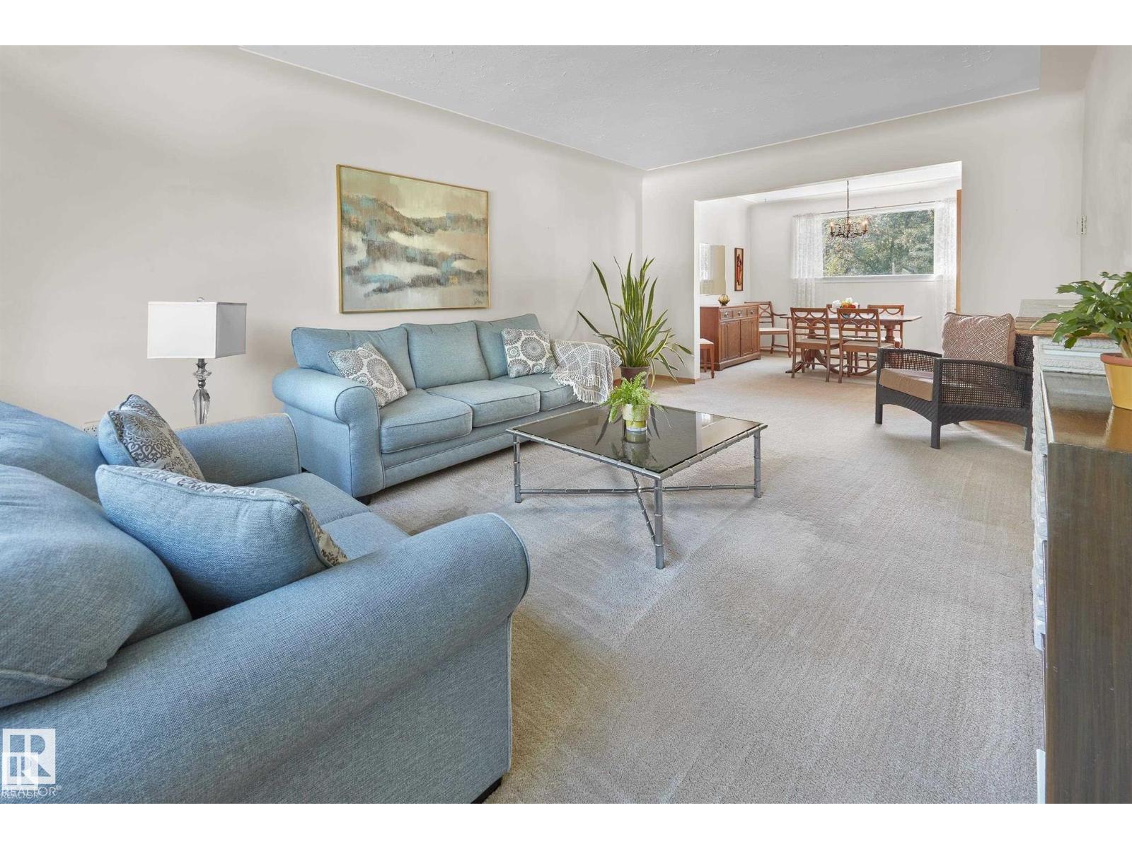 A living room with a blue couch and a glass coffee table.