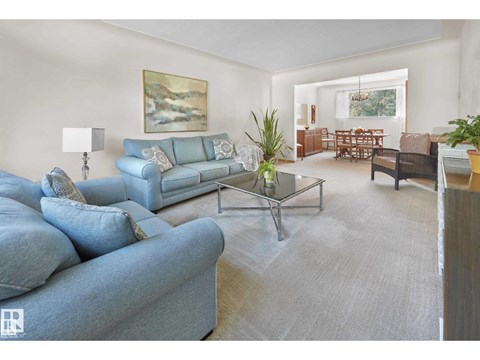 A living room with a blue couch and a glass coffee table.