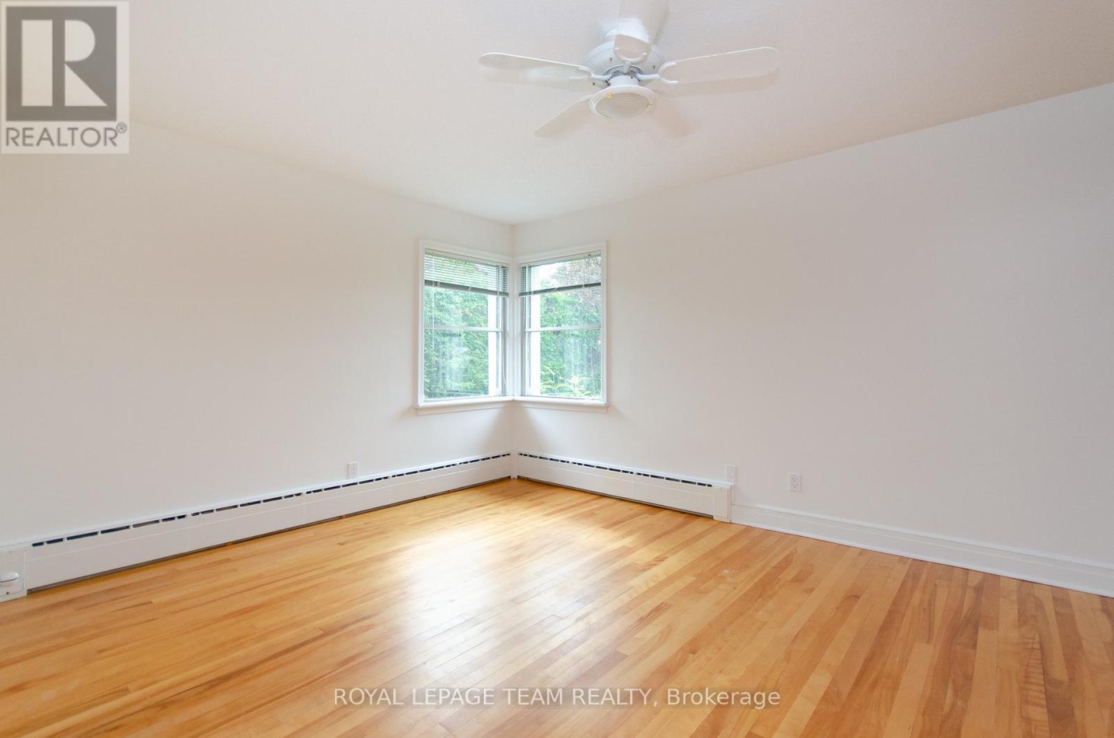 A room with a ceiling fan and a window with a view of trees.