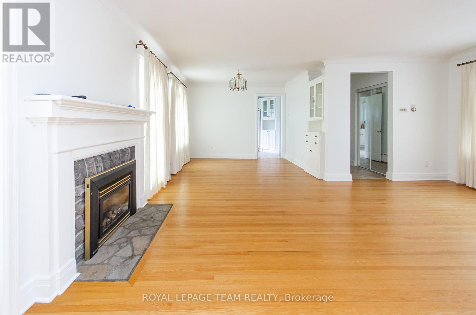 A spacious room with a fireplace and wooden floors.