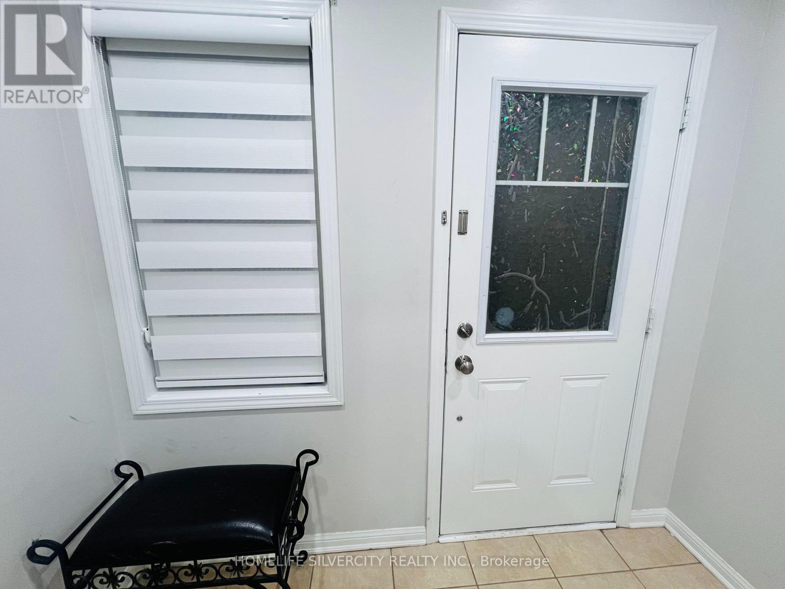 A white door with a glass window is next to a window with white blinds.