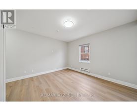 A spacious room with a window and wooden flooring.