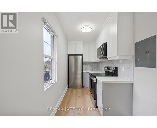 A kitchen with white cabinets and a stainless steel refrigerator.