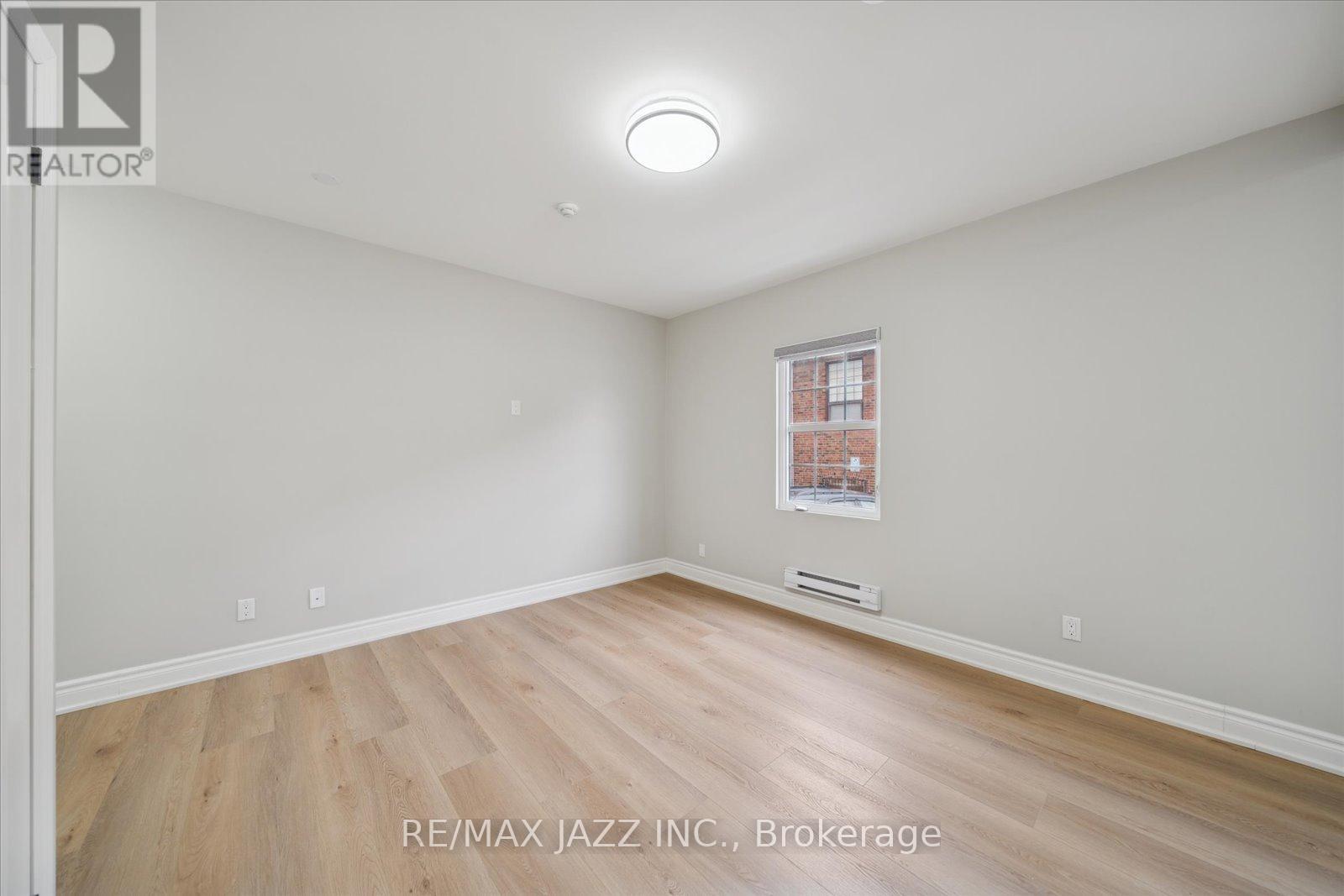 A spacious room with a window and wooden flooring.