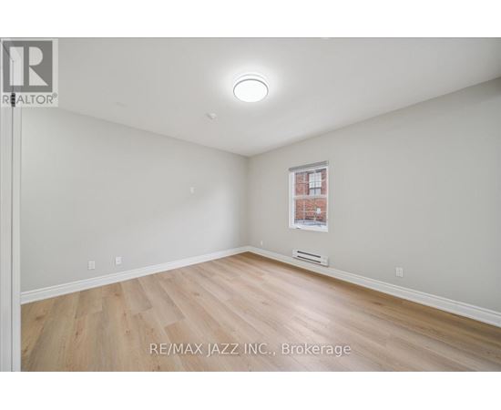 A spacious room with a window and wooden flooring.