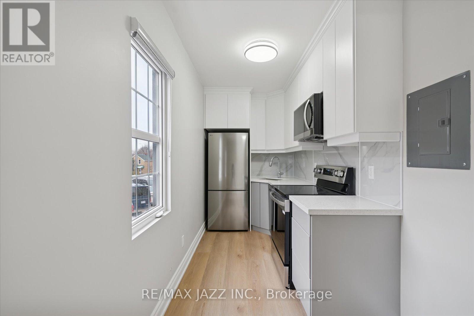 A kitchen with white cabinets and a stainless steel refrigerator.