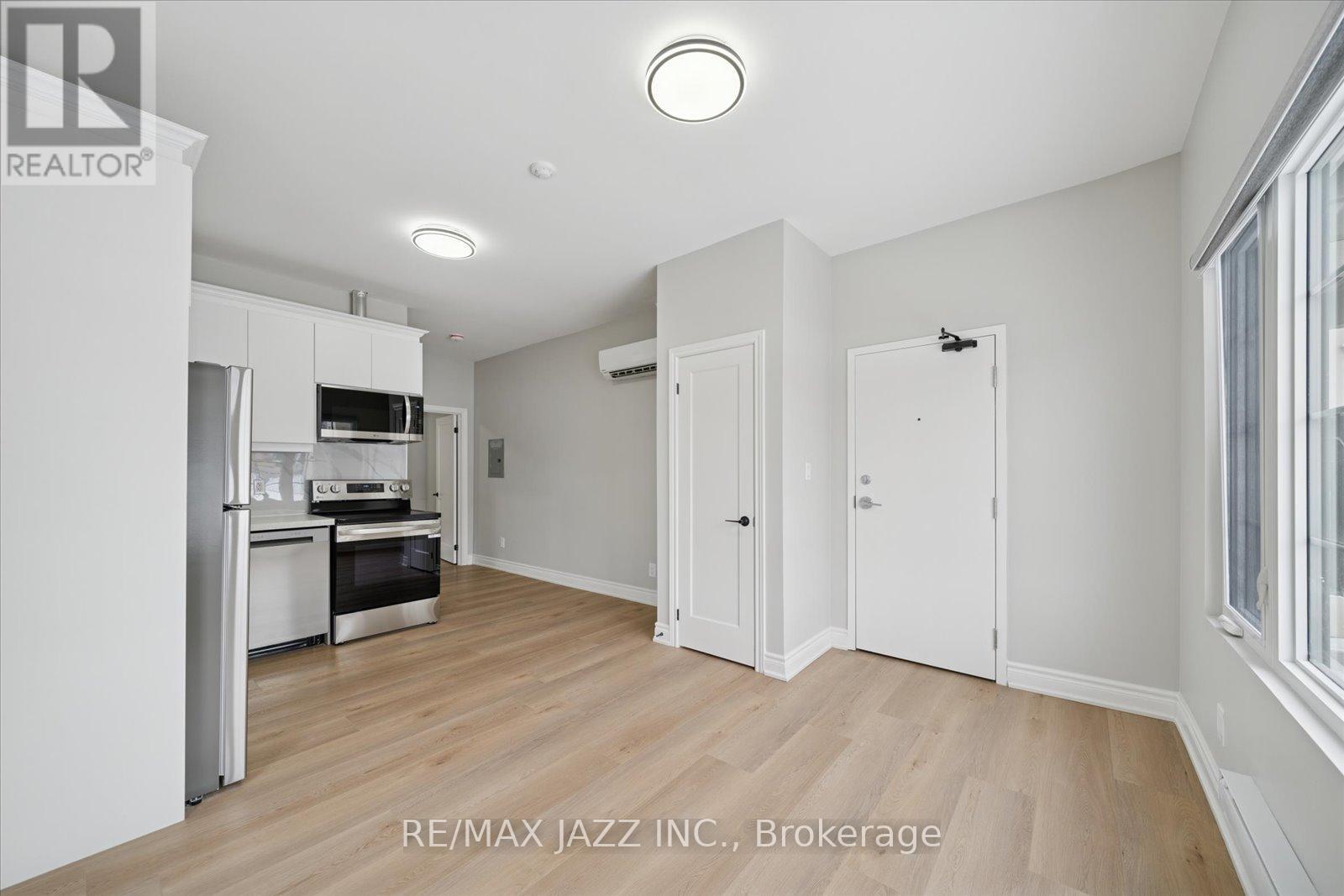 A spacious kitchen with white cabinets and a wooden floor.