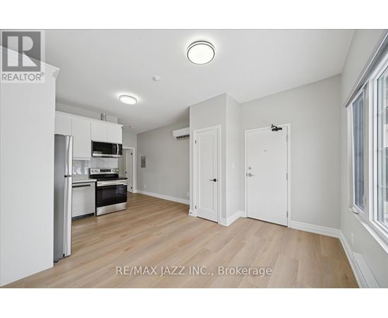 A spacious kitchen with white cabinets and a wooden floor.