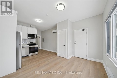 A spacious kitchen with white cabinets and a wooden floor.