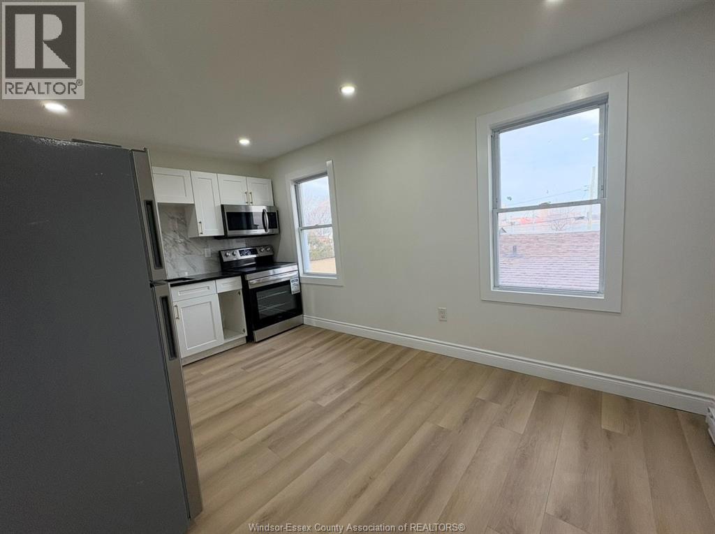 A kitchen with a refrigerator, microwave, and oven.