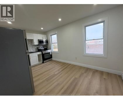 A kitchen with a refrigerator, microwave, and oven.