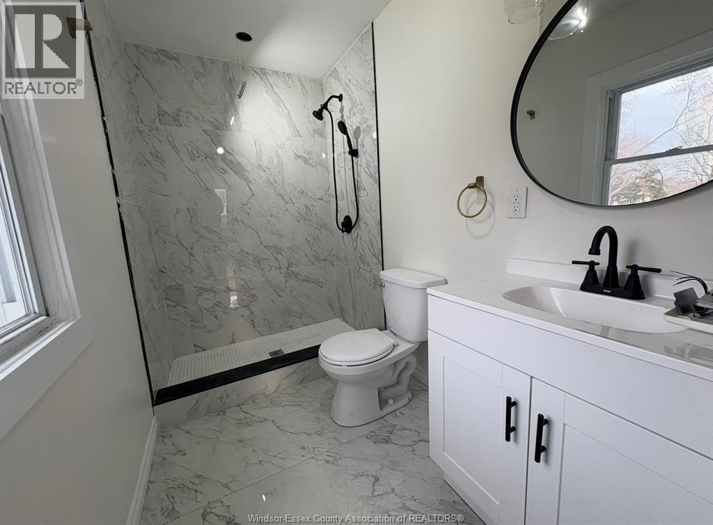 A bathroom with a marble shower and white toilet.