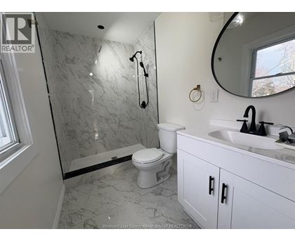 A bathroom with a marble shower and white toilet.