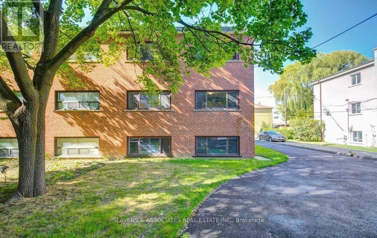 A red brick building with a tree in front of it.