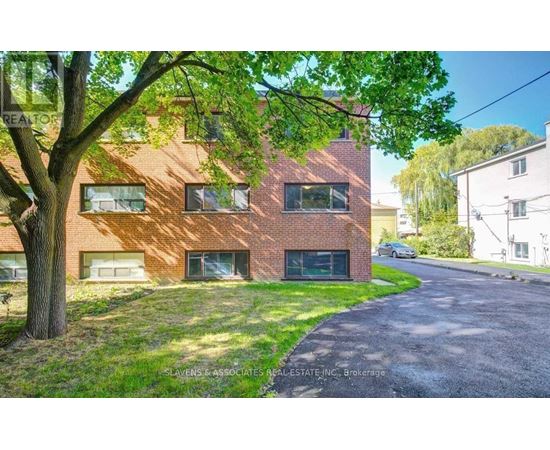 A red brick building with a tree in front of it.