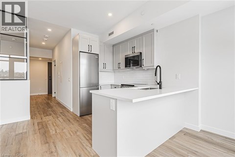 A modern kitchen with white cabinets and a wooden floor.