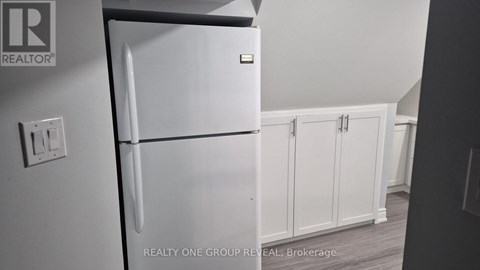 A white refrigerator in a kitchen with a brokerage logo.