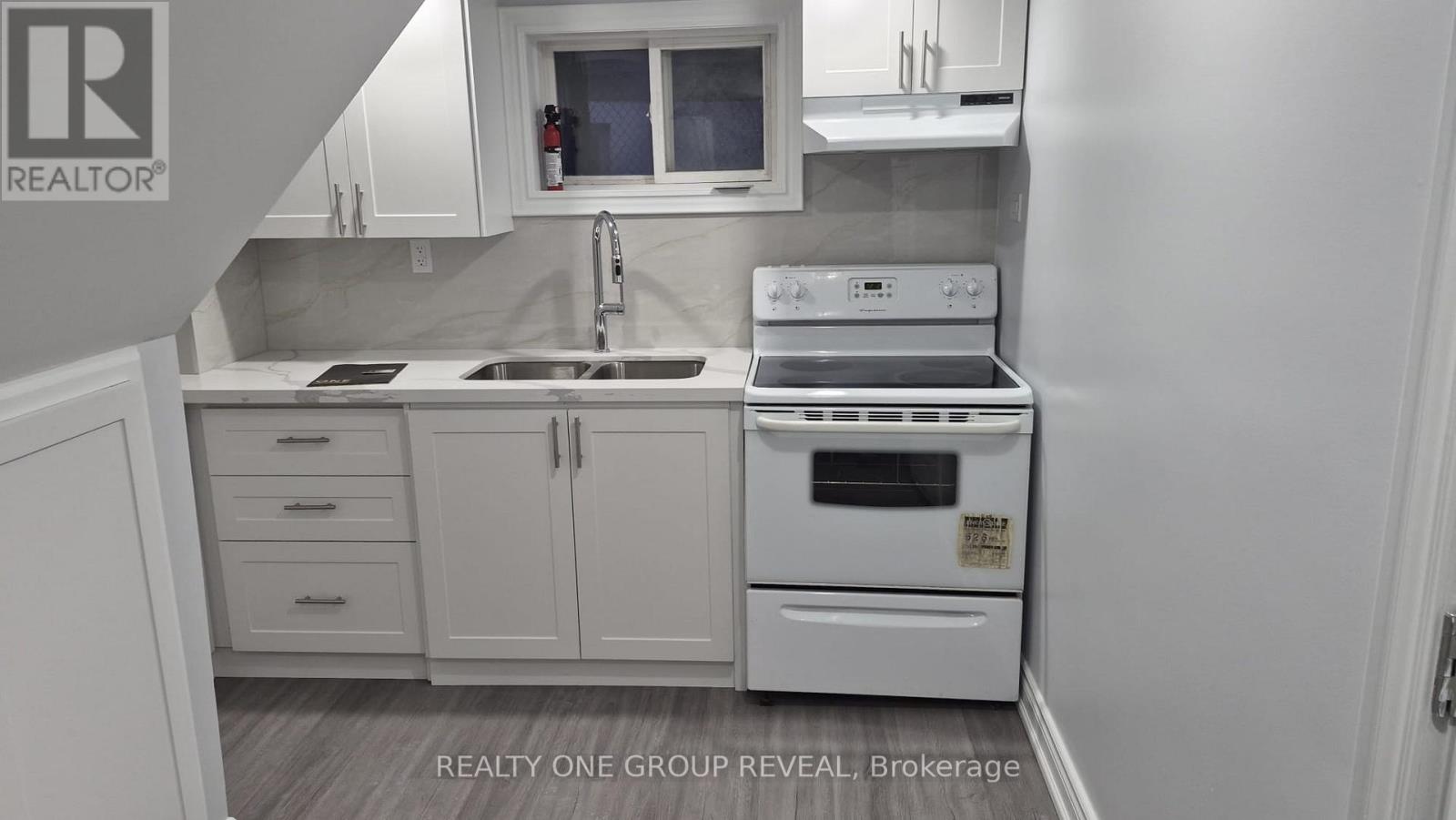 A white kitchen with a sink, stove, and cabinets.