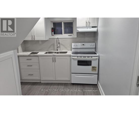 A white kitchen with a sink, stove, and cabinets.