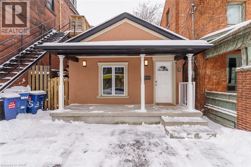 A house with a brown roof and a white door is surrounded by snow.