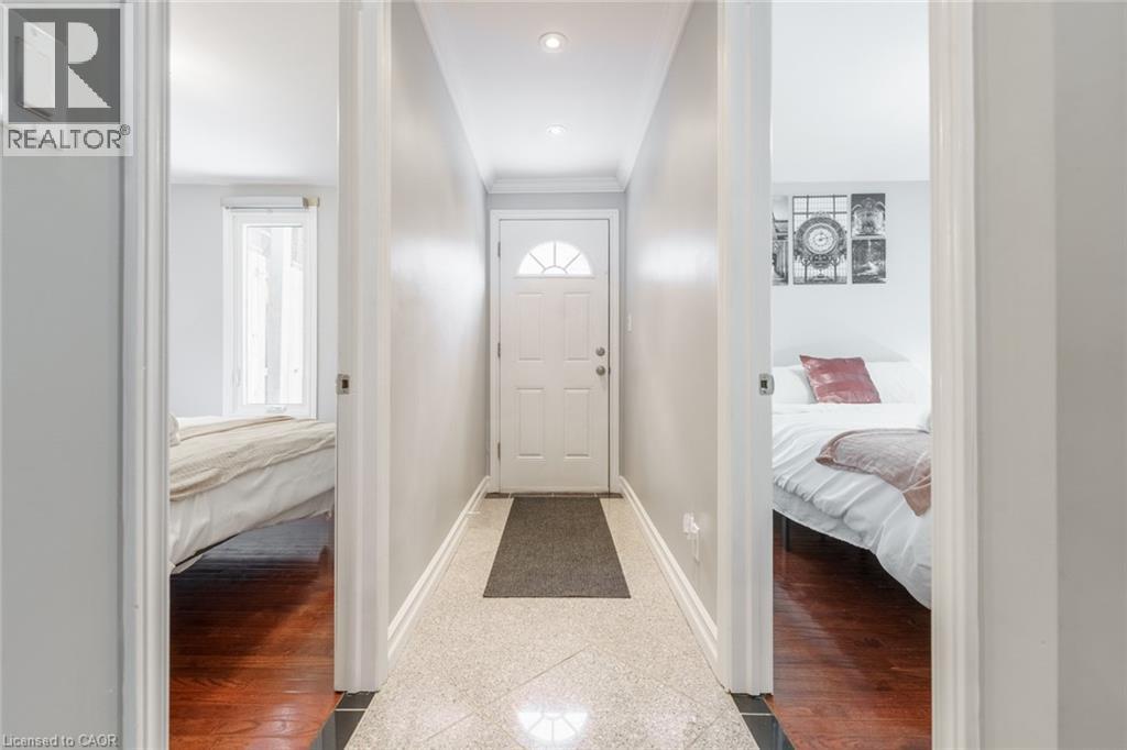 A hallway with a rug in the middle leading to a bedroom and a bed.