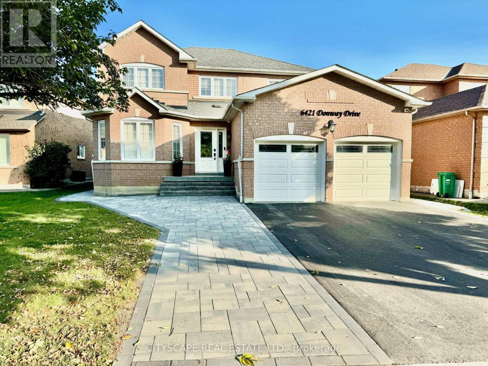 A brick house with a driveway in front of it.