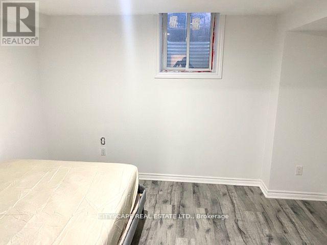 A bedroom with a bed, wooden floor, and a window with blinds.