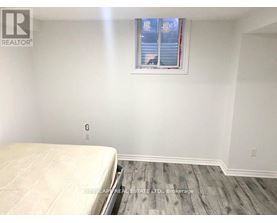A bedroom with a bed, wooden floor, and a window with blinds.