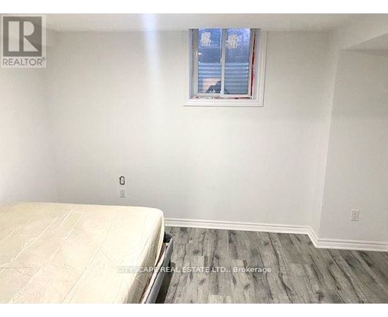 A bedroom with a bed, wooden floor, and a window with blinds.