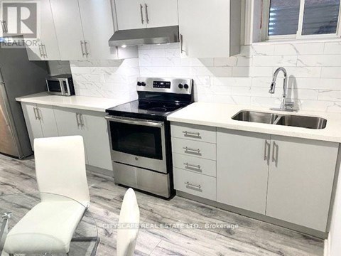 A modern kitchen with white cabinets and a marble backsplash.