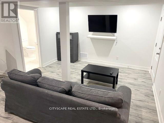 A living room with a grey couch, a black coffee table, and a flat screen TV mounted on the wall.