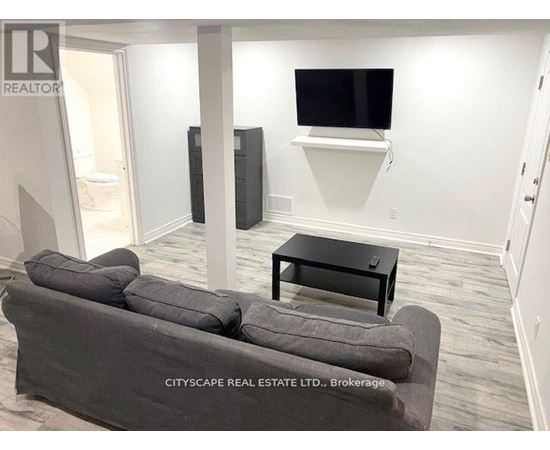 A living room with a grey couch, a black coffee table, and a flat screen TV mounted on the wall.