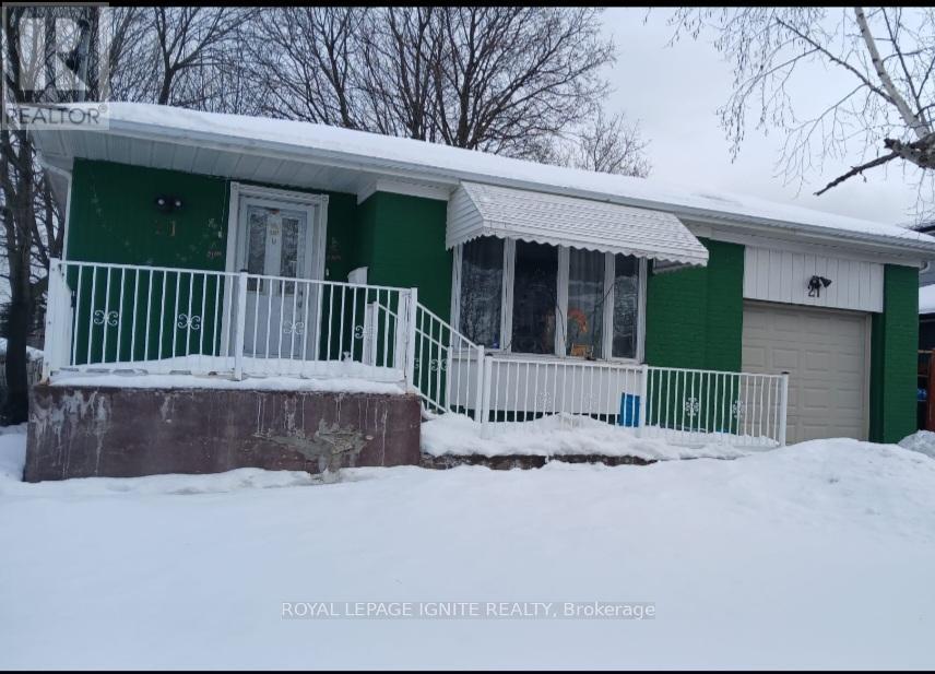 A green house with a white fence and a small porch.