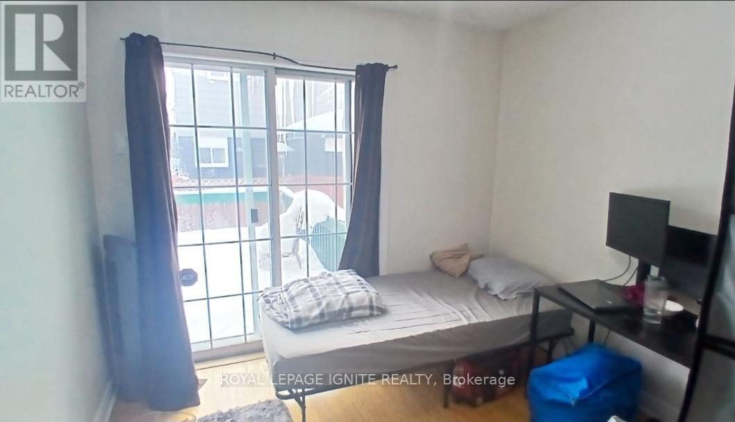 A bedroom with a bed, a desk, and a window with curtains.