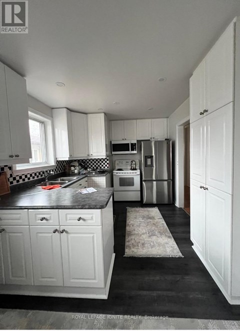 A kitchen with white cabinets and a black countertop.
