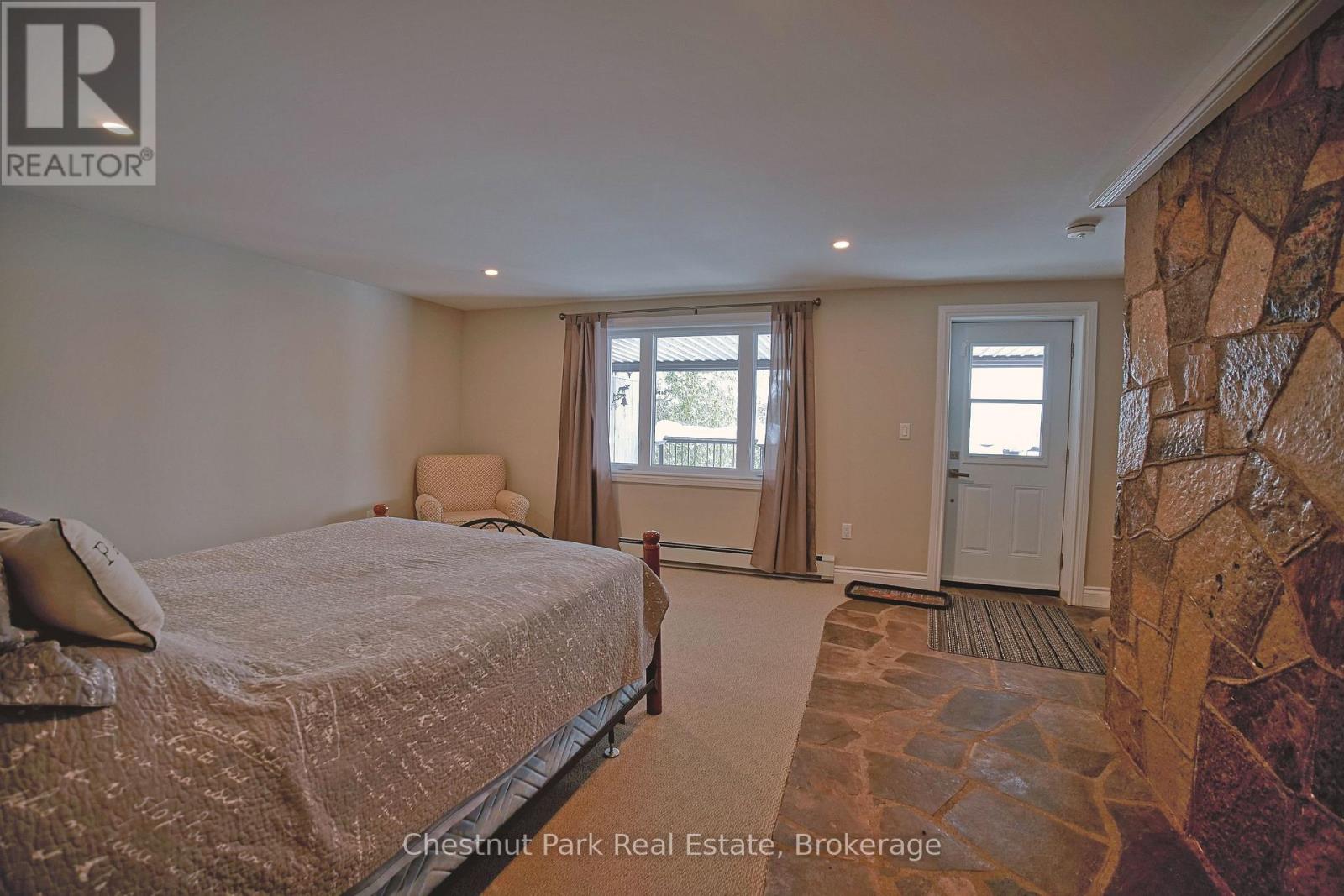A bedroom with a large bed and a stone wall.