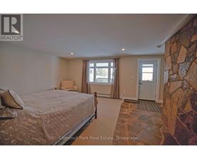 A bedroom with a large bed and a stone wall.