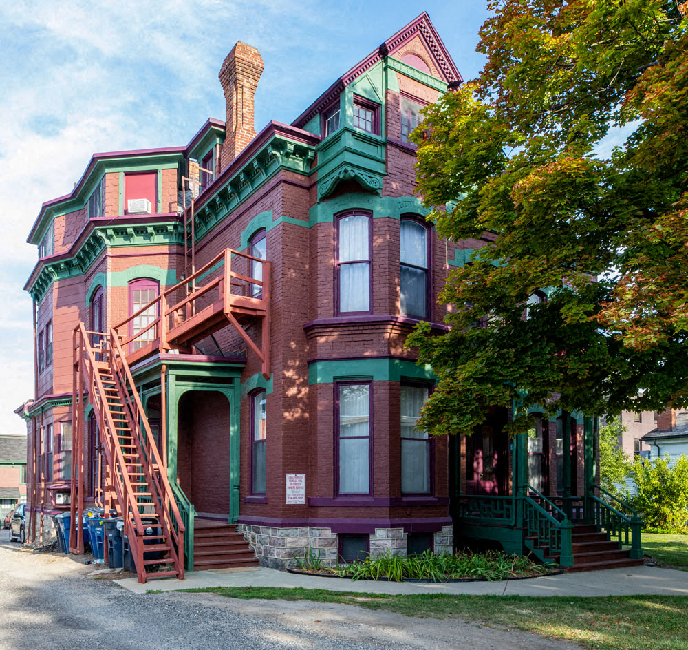 a red brick house with green and red stairs