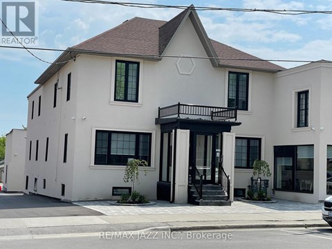 A white two-story house with a balcony on the second floor.