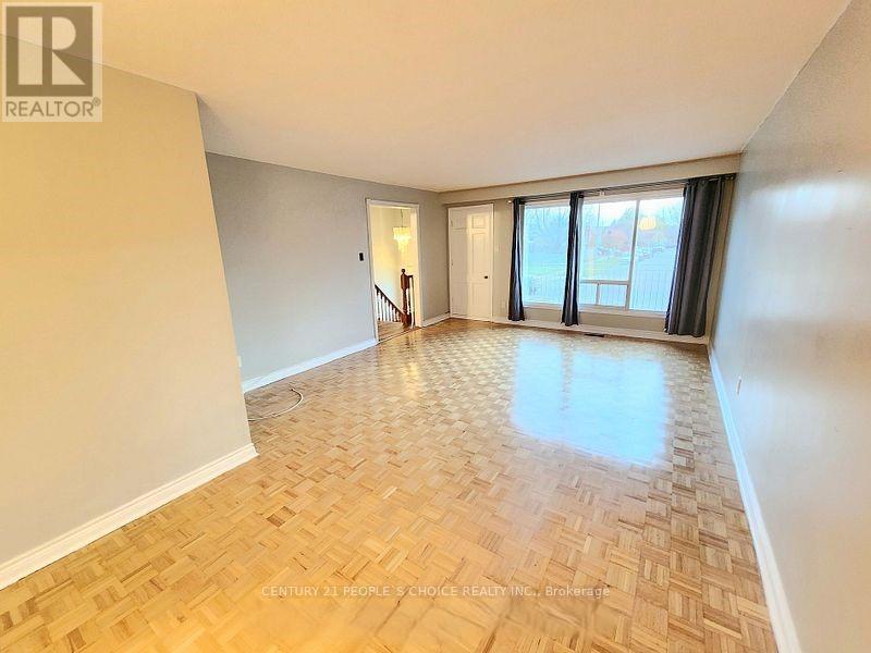 A spacious room with wooden flooring and a large window.